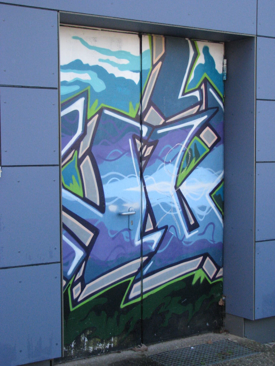 Graffiti in Blau und Grün an der Wilhelm Baum Turnhalle